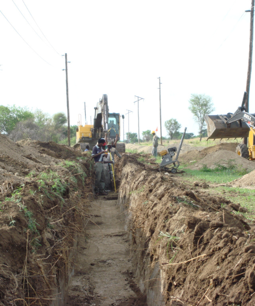 A construction crew digging a trench in a field