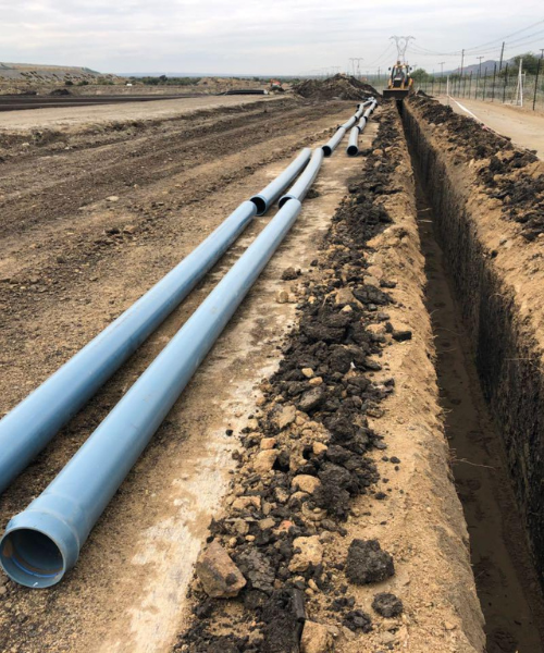 A large pipe laying on top of a dirt field