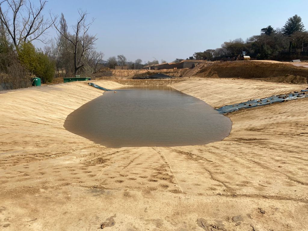 A large body of water sitting in the middle of a dirt field